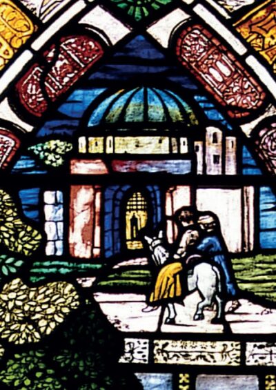 Mary and Joseph travel on a donkey, surrounded by lush greenery and a detailed architectural backdrop in stained glass