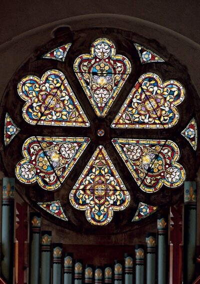 Stained glass rose window featuring intricate floral patterns and vibrant colors, set against a dark background