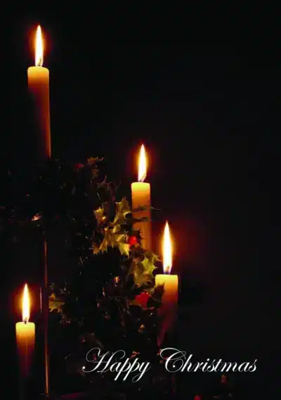 Four lit candles surrounded by holly leaves, with "Happy Christmas" elegantly written below on a dark background